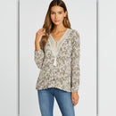 Woman wearing a floral blouse and blue jeans on a light gray background