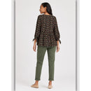 Woman wearing a floral blouse and green pants on a white background