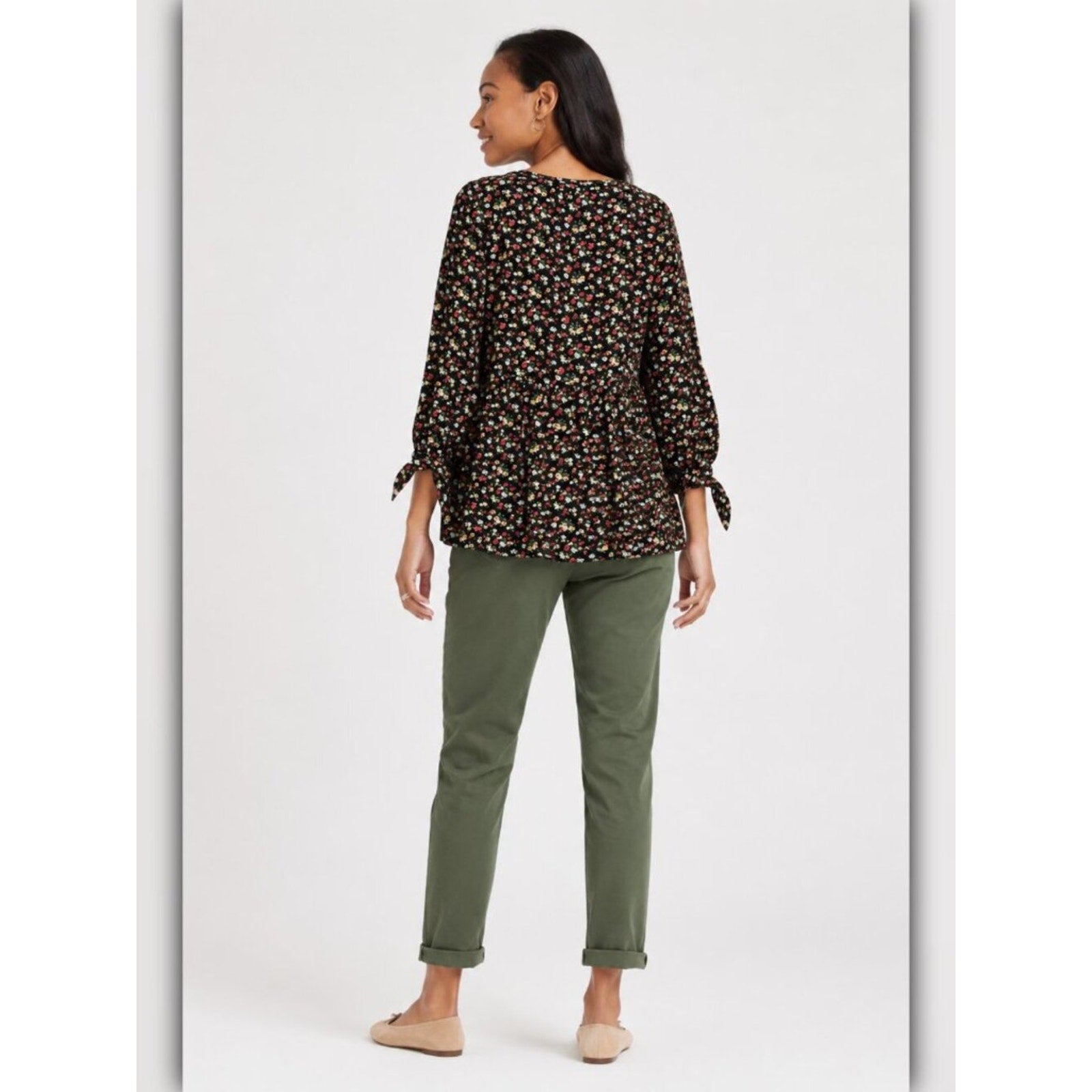 Woman wearing a floral blouse and green pants on a white background