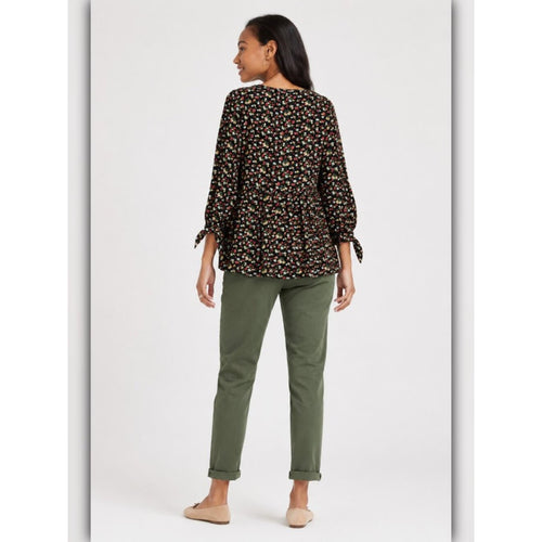 Woman wearing a floral blouse and green pants on a white background