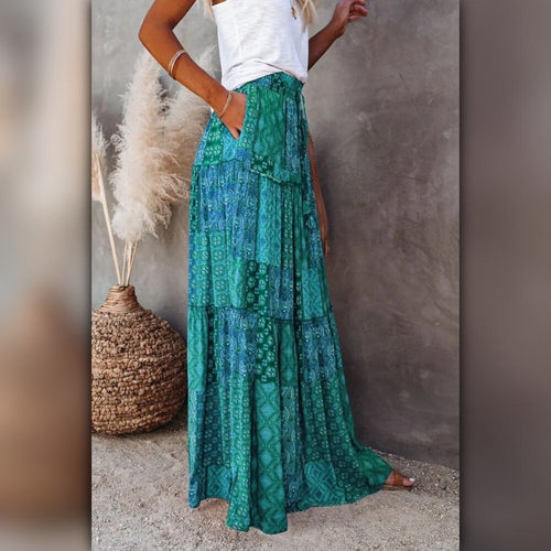 Person wearing a green patterned skirt standing against a neutral wall.