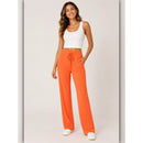 Woman wearing orange pants and a white top on a light background