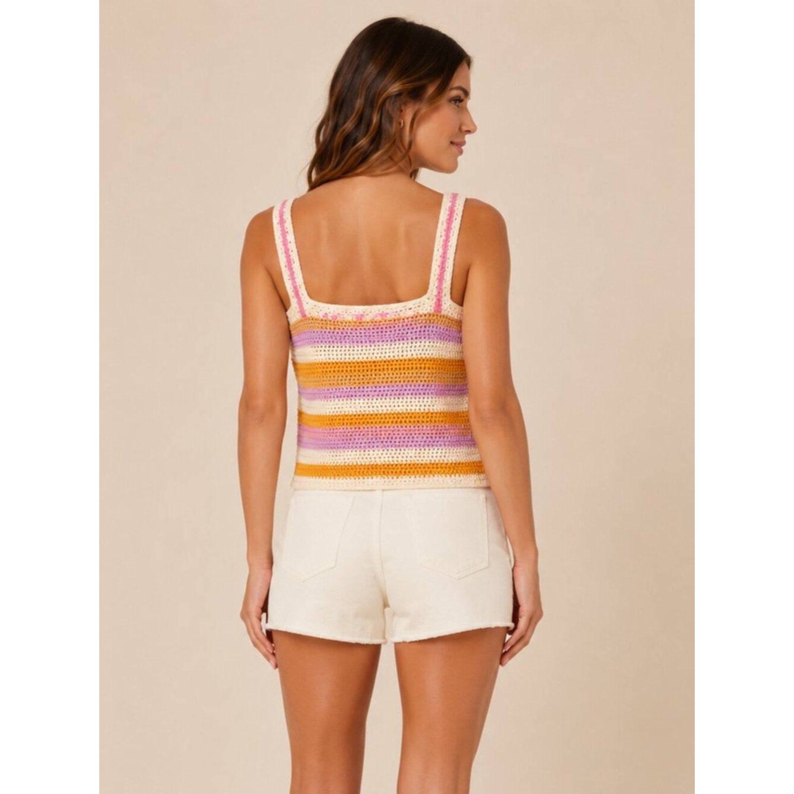 Woman wearing a colorful striped tank top and white shorts on a beige background