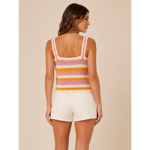 Woman wearing a colorful striped tank top and white shorts on a beige background
