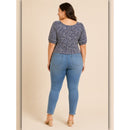 Woman wearing a patterned top and blue jeans on a beige background