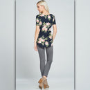 Woman wearing a navy floral top and gray pants on a light gray background