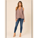 Woman wearing a mauve top and blue jeans on a beige background