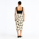 Woman wearing a black top and patterned skirt on a white background