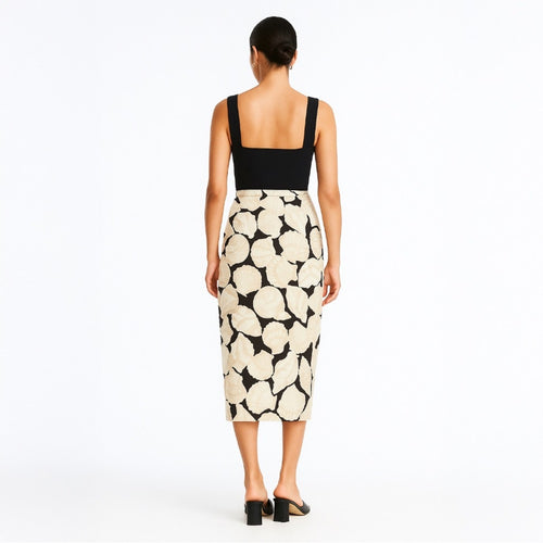Woman wearing a black top and patterned skirt on a white background