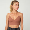 Woman wearing a brown ribbed crop top against a plain background