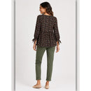 Woman wearing a patterned blouse and green pants on a white background