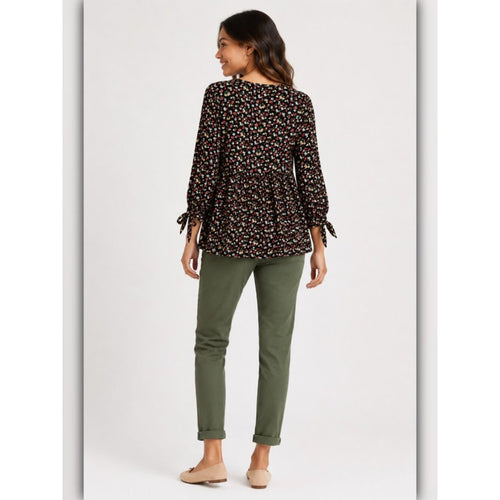 Woman wearing a patterned blouse and green pants on a white background