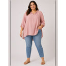 Woman wearing a pink shirt and blue jeans on a plain background