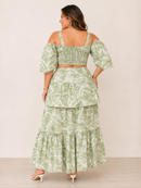 Woman wearing a green floral two-piece outfit against a beige background
