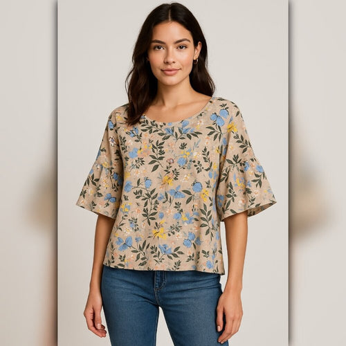 Woman wearing a floral blouse and jeans against a plain background