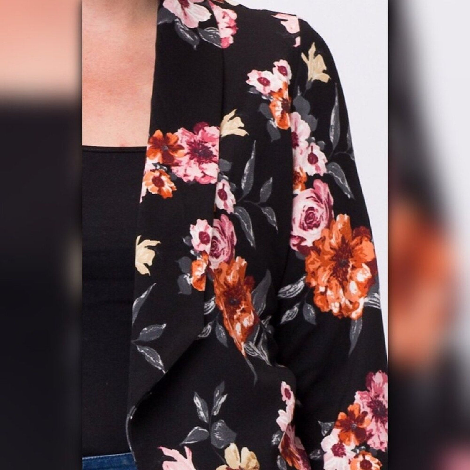 Close up of black floral blazer fabric with pink, orange, cream, and gray floral print detail.