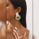 Close-up of a woman wearing colorful hoop earrings with a neutral background