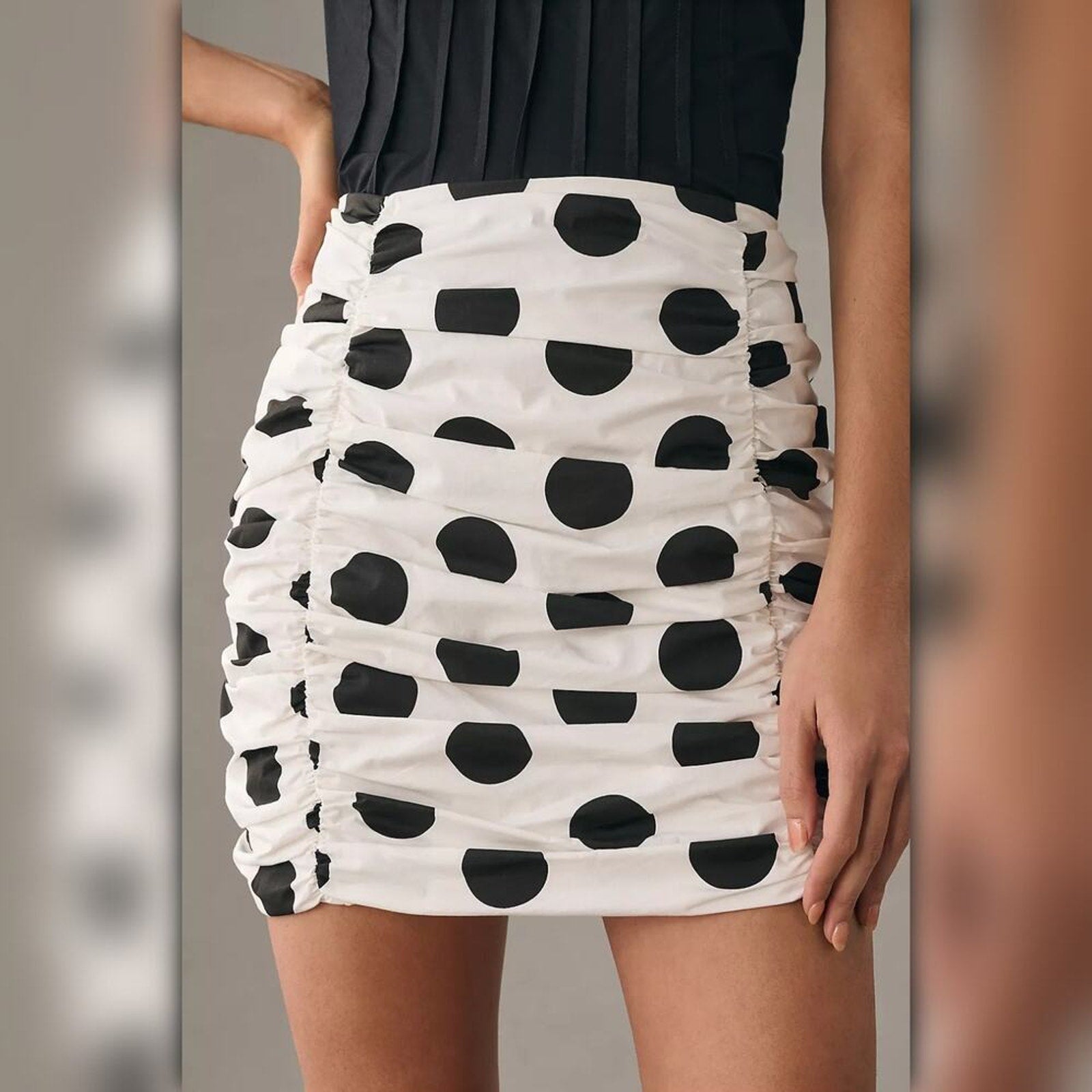 White skirt with black polka dots worn by a person against a neutral background