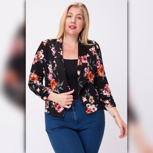 Plus size model wearing a black floral open front blazer with 3/4 sleeves, styled with a black top and blue jeans.