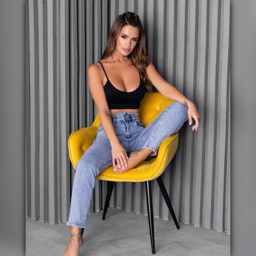 Woman sitting on a yellow chair against a gray corrugated metal background