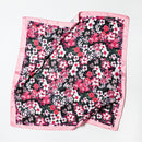 Black satin floral scarf with pink border shown partially folded to highlight sheen and pattern detail