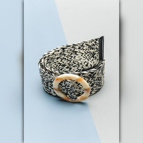 Black and white patterned belt with a beige buckle on a light blue and gray background