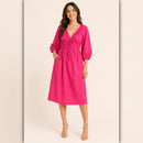Woman wearing a bright pink dress on a beige background