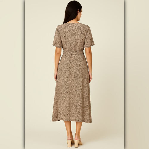 A woman viewed from the back wearing a short-sleeve midi dress with a beige and brown animal print pattern, paired with beige block-heel mules, set against a solid light beige studio background.