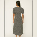 Woman wearing a patterned dress against a plain background