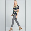 Woman wearing a floral top and gray jeans on a light gray background