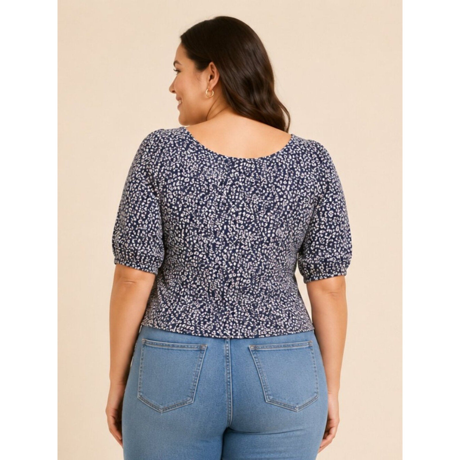 Woman wearing a blue floral top and jeans on a beige background