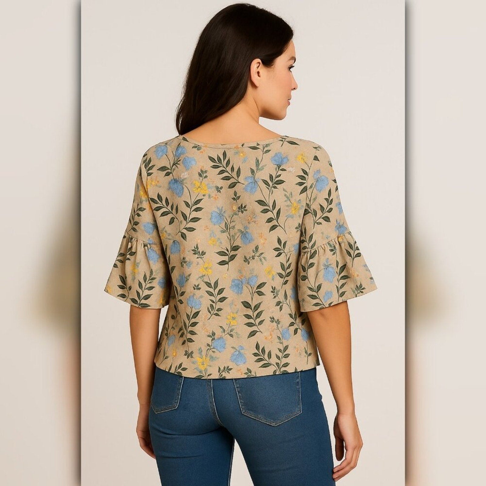 Woman wearing a floral-patterned top and blue jeans on a plain background