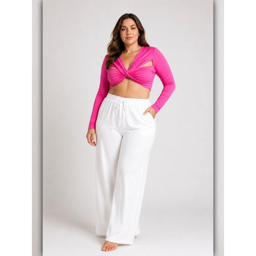 Woman wearing a bright pink long-sleeve top and white pants on a light gray background