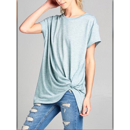 Woman wearing a light blue t-shirt and ripped jeans on a gray background