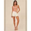 Woman wearing a colorful tank top and white shorts on a beige background