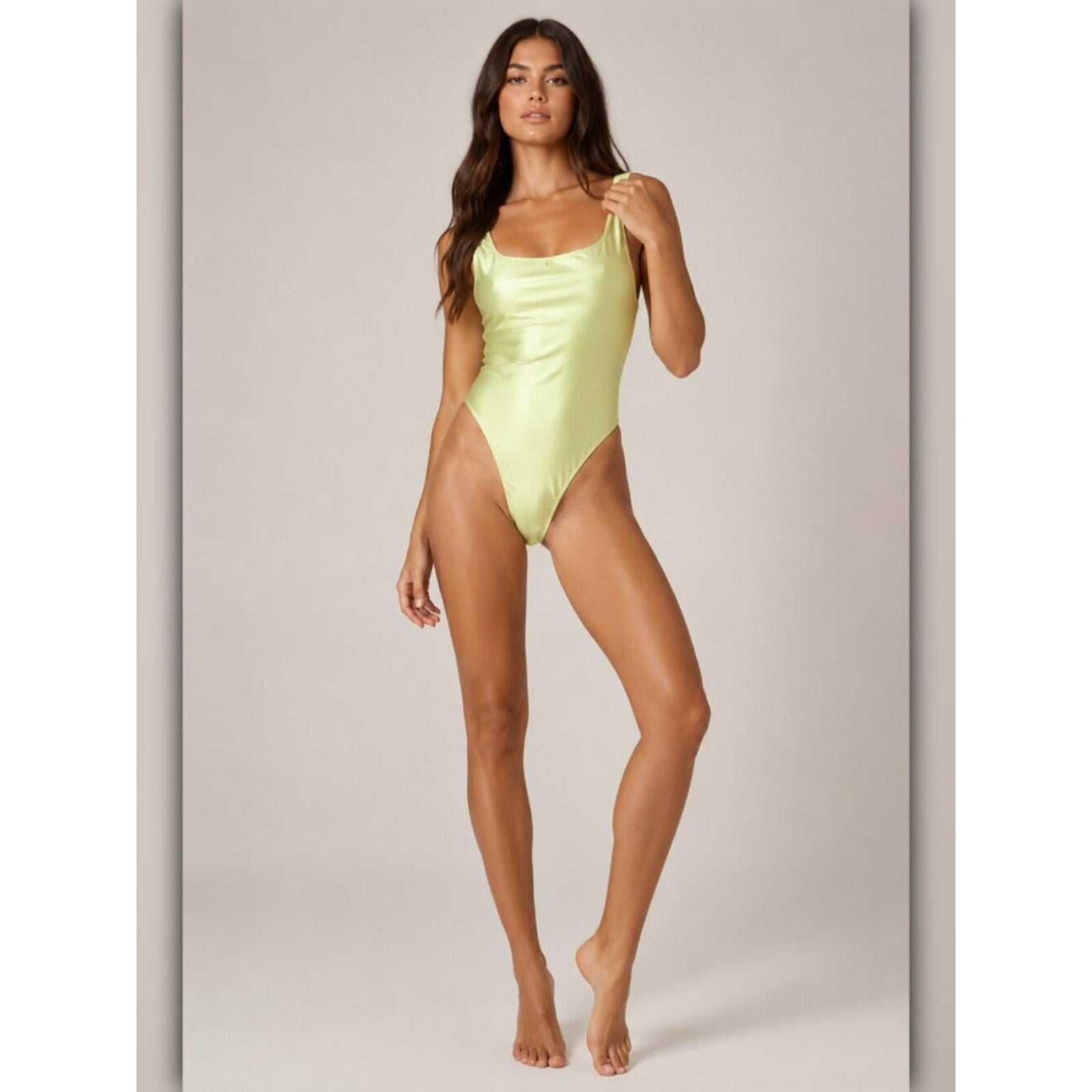 Woman wearing a light green swimsuit against a neutral background