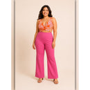 Woman wearing a floral top and pink pants on a beige background