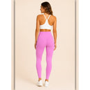 Woman wearing pink leggings and a white sports bra on a beige background