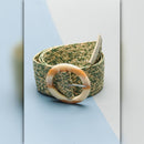 Green woven belt with a beige buckle on a light blue background