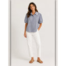 Woman wearing a blue and white striped shirt and white pants on a white background