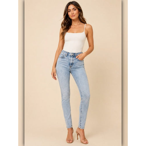 Woman wearing light blue jeans and a white top on a beige background