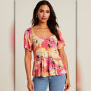 Woman wearing a colorful floral blouse against a neutral background