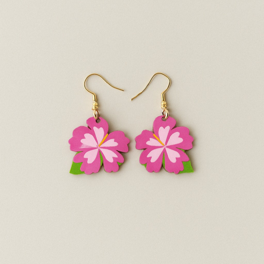Flower-shaped earrings with pink flowers and green leaves on a beige background