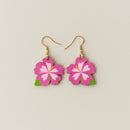 Flower-shaped earrings with pink flowers and green leaves on a beige background