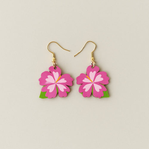Flower-shaped earrings with pink flowers and green leaves on a beige background